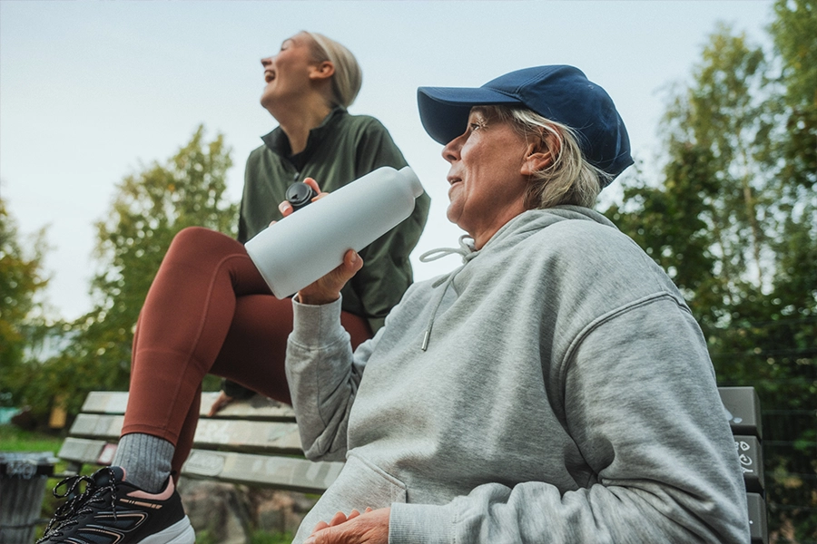 Two people in active outfits outdoors sitting on bench